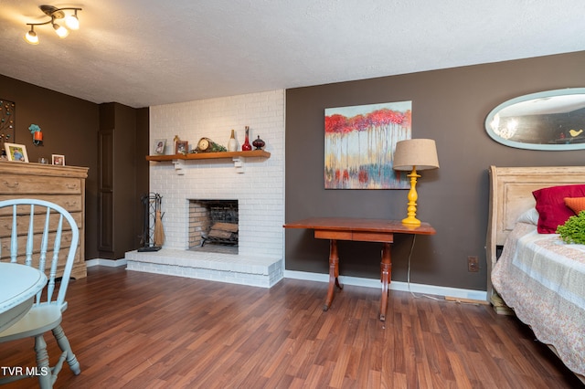 living room with a fireplace, brick wall, hardwood / wood-style floors, and a textured ceiling