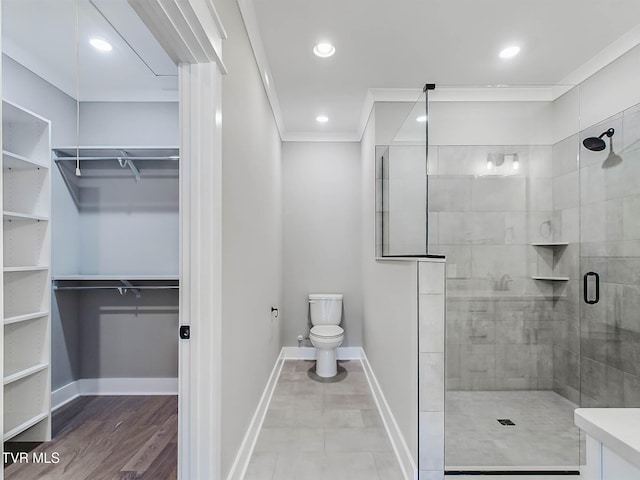 bathroom featuring vanity, toilet, a shower with shower door, and crown molding