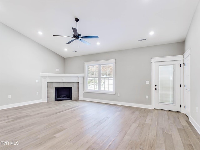 unfurnished living room with ceiling fan, a tile fireplace, and light hardwood / wood-style flooring