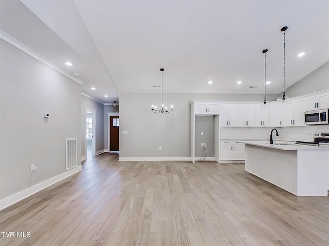 kitchen featuring pendant lighting, range with electric stovetop, white cabinets, and a center island with sink