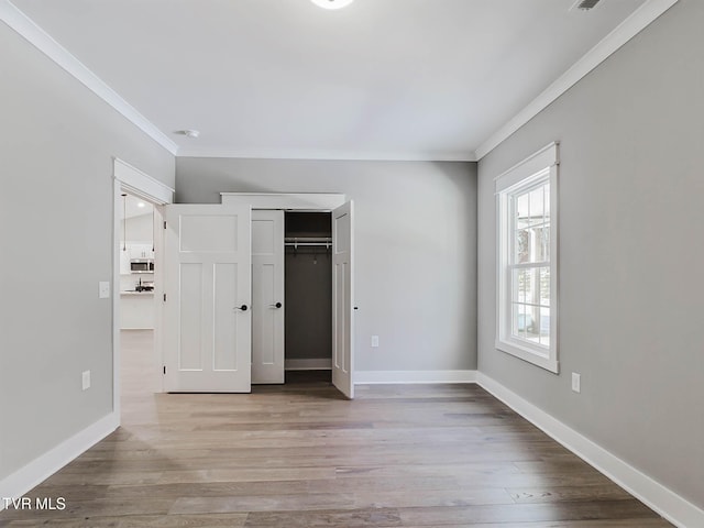 unfurnished bedroom with light wood-type flooring, a closet, and crown molding