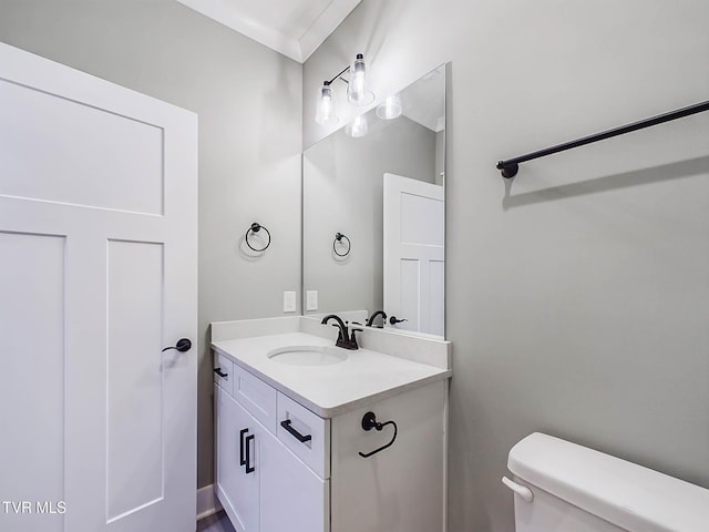 bathroom featuring vanity, ornamental molding, and toilet