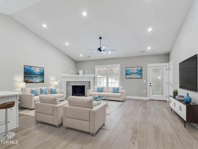 living room with a fireplace, vaulted ceiling, light hardwood / wood-style flooring, and ceiling fan