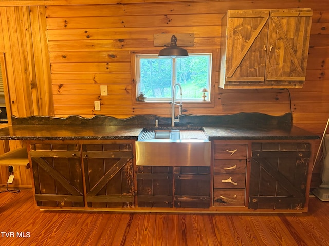 kitchen featuring hardwood / wood-style floors, wood walls, and sink