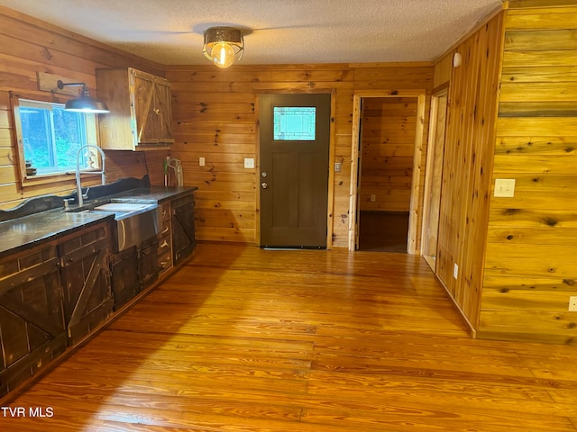 kitchen featuring a textured ceiling, wood walls, and sink