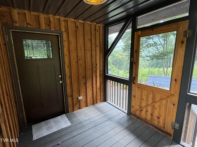 doorway with wooden walls and light hardwood / wood-style flooring