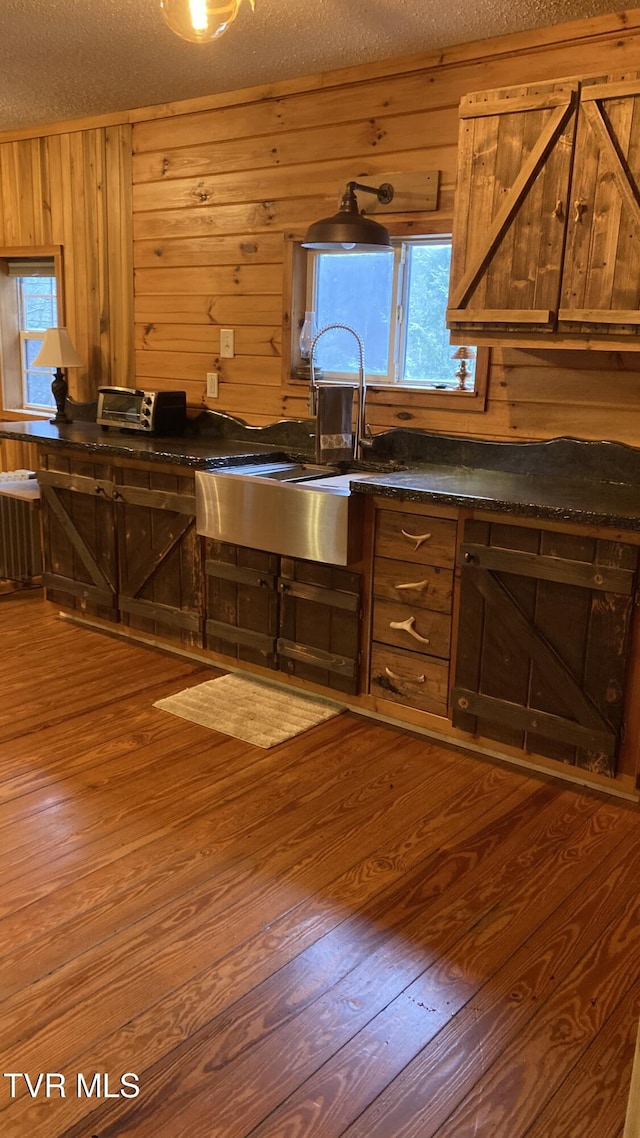 kitchen featuring hardwood / wood-style floors, a textured ceiling, and wooden walls