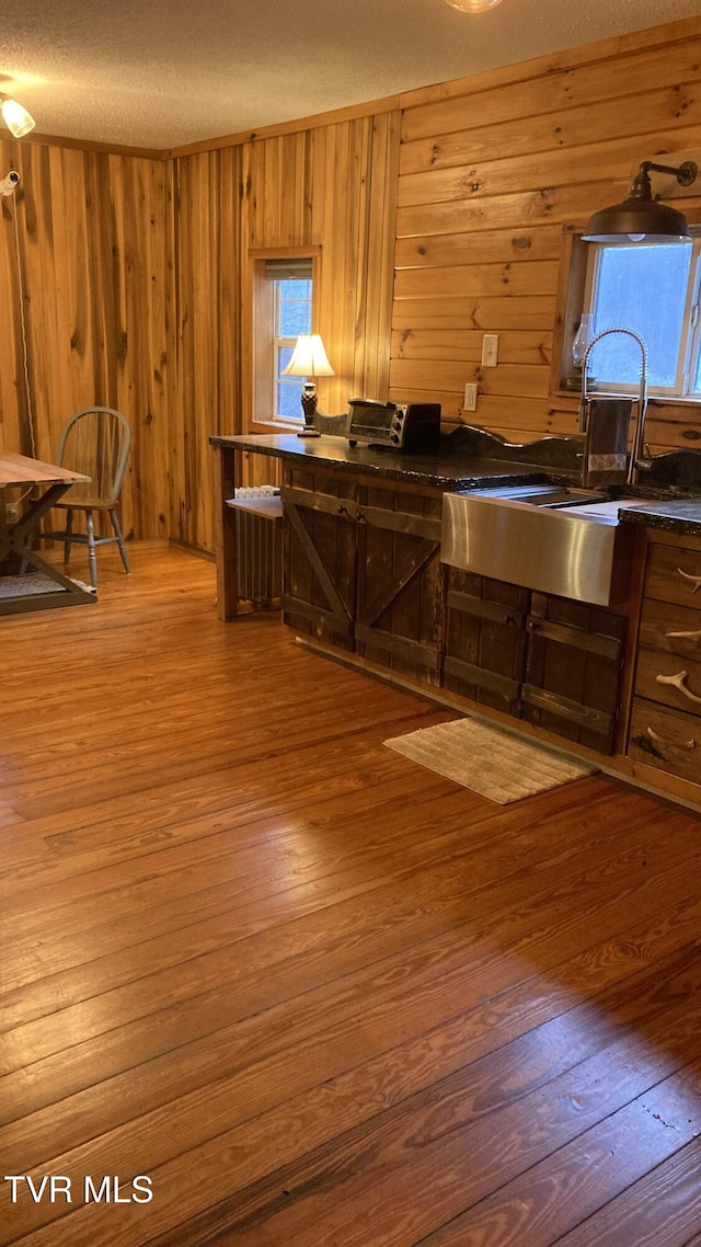 kitchen with wood walls, sink, a textured ceiling, and hardwood / wood-style flooring