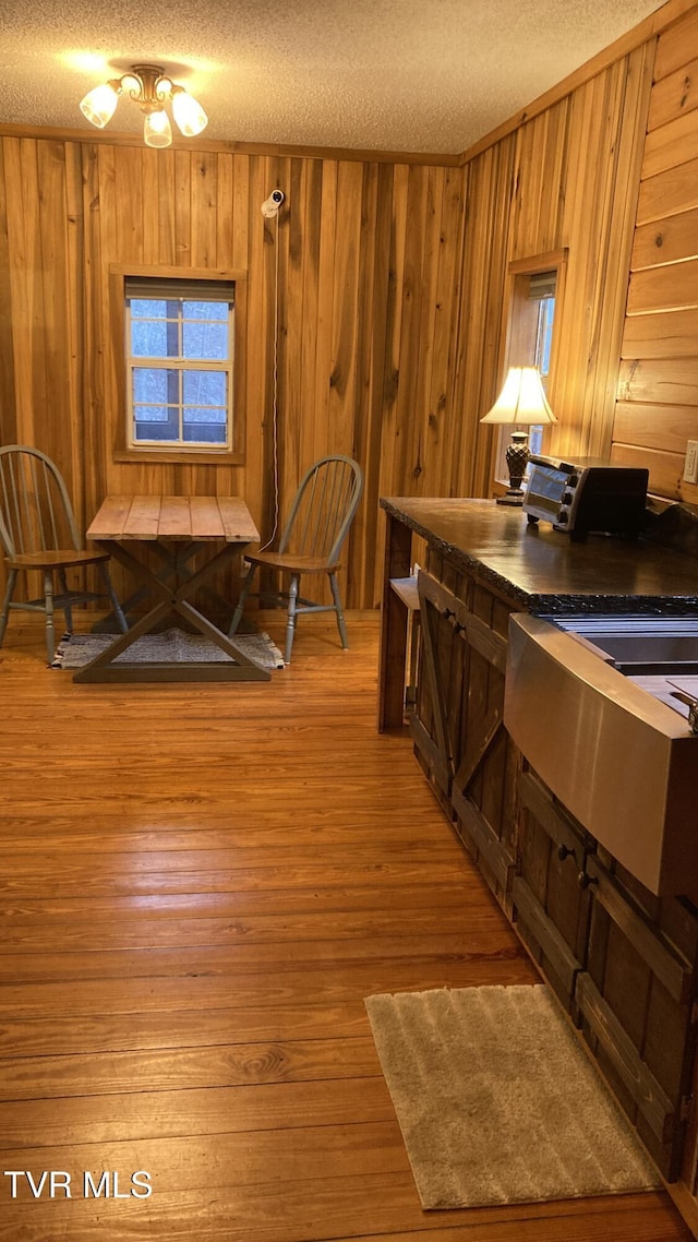 kitchen with wood-type flooring, a textured ceiling, and wood walls