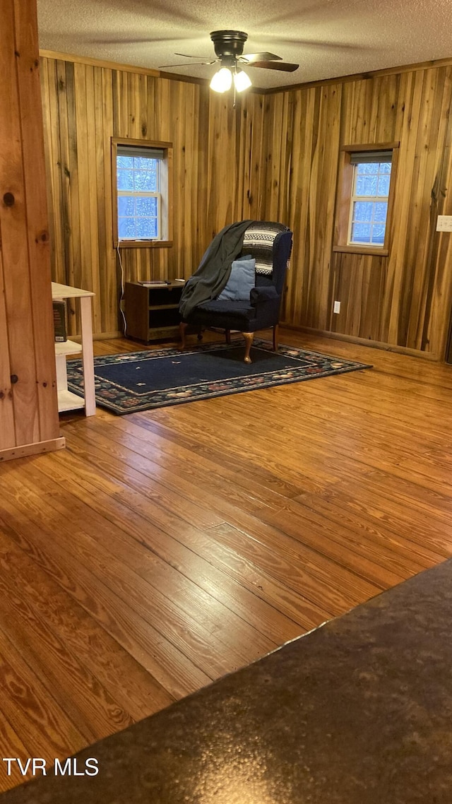 unfurnished room featuring ceiling fan, wood walls, and a textured ceiling