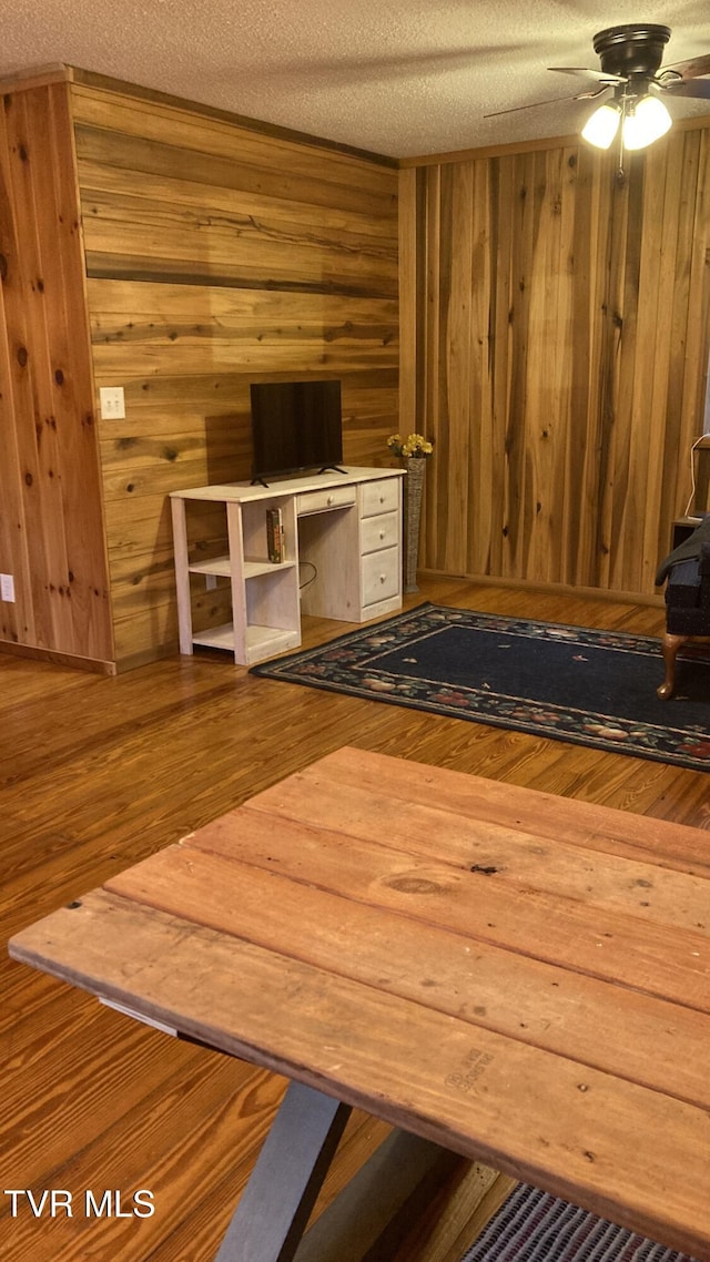 interior space with ceiling fan, wood-type flooring, and a textured ceiling