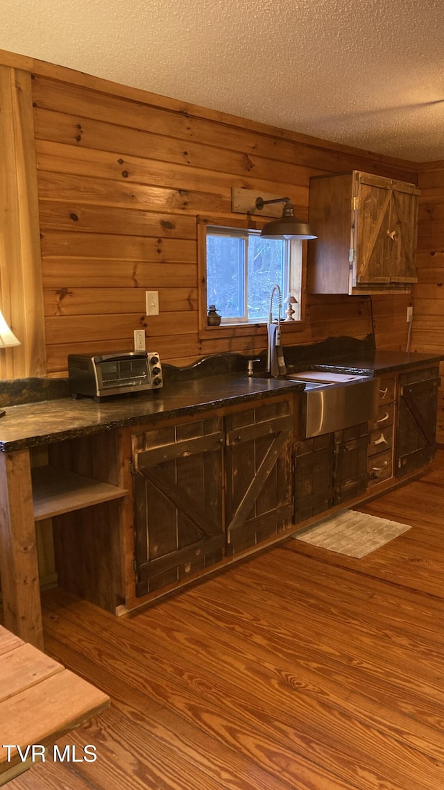 kitchen with wood walls, light hardwood / wood-style floors, and a textured ceiling