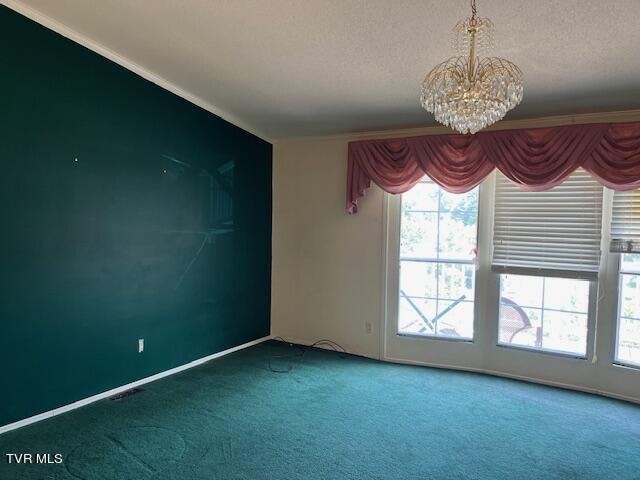 carpeted spare room with a chandelier, a textured ceiling, and a wealth of natural light