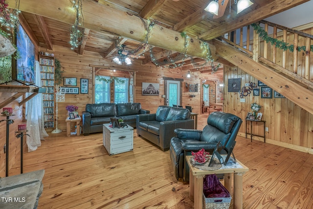 living room with wooden walls, beam ceiling, and light hardwood / wood-style floors