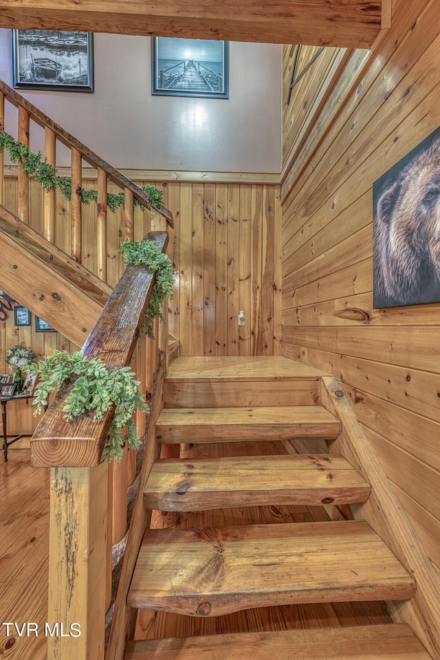 stairway featuring wooden walls