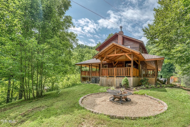 back of property with a yard, a deck, and an outdoor fire pit