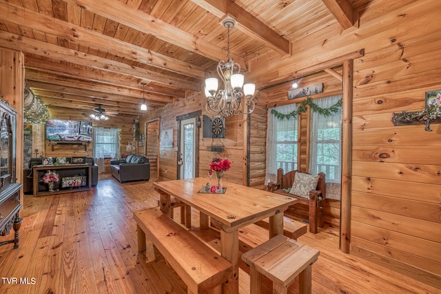 dining area featuring wood ceiling, beam ceiling, wooden walls, ceiling fan with notable chandelier, and light hardwood / wood-style floors