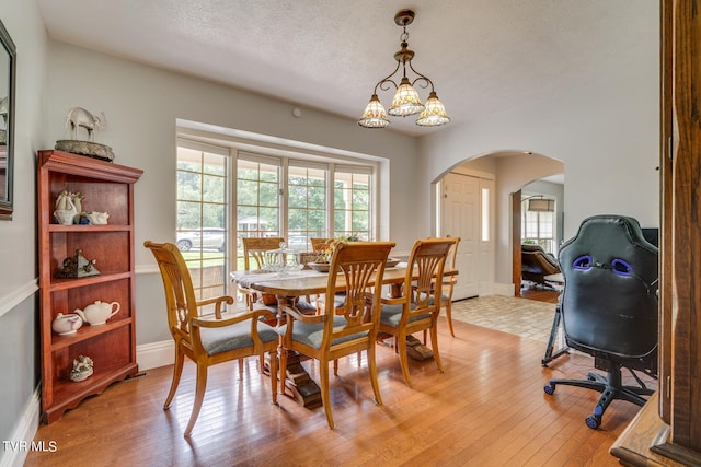 dining room with a textured ceiling, a chandelier, and light wood-type flooring