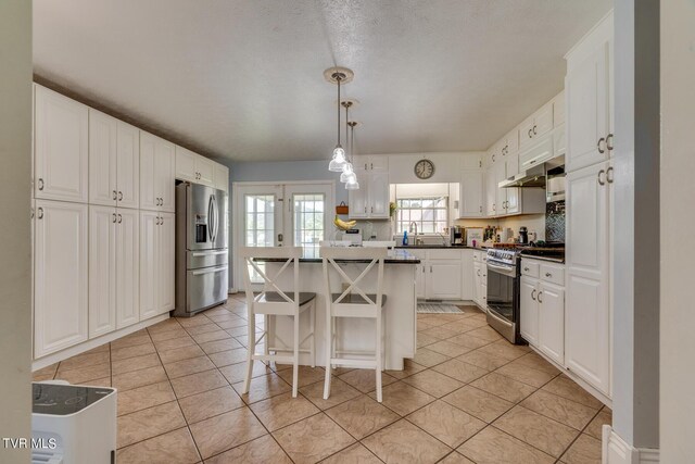 kitchen featuring a breakfast bar, appliances with stainless steel finishes, a kitchen island, light tile patterned floors, and white cabinets