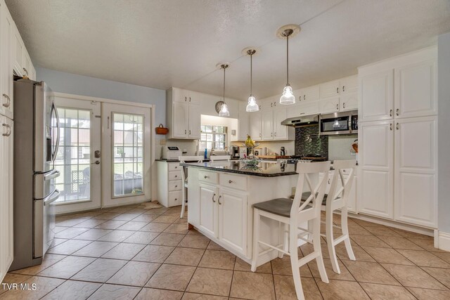 kitchen featuring a wealth of natural light, appliances with stainless steel finishes, a kitchen island, and white cabinets