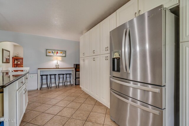 kitchen featuring white cabinetry, light tile patterned floors, and stainless steel refrigerator with ice dispenser