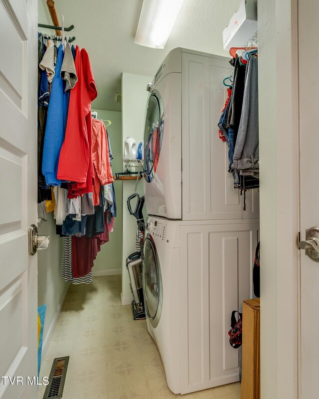 laundry room featuring stacked washer / drying machine and light tile patterned flooring