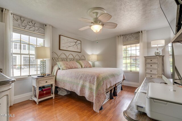 bedroom featuring a textured ceiling, ceiling fan, and light wood-type flooring