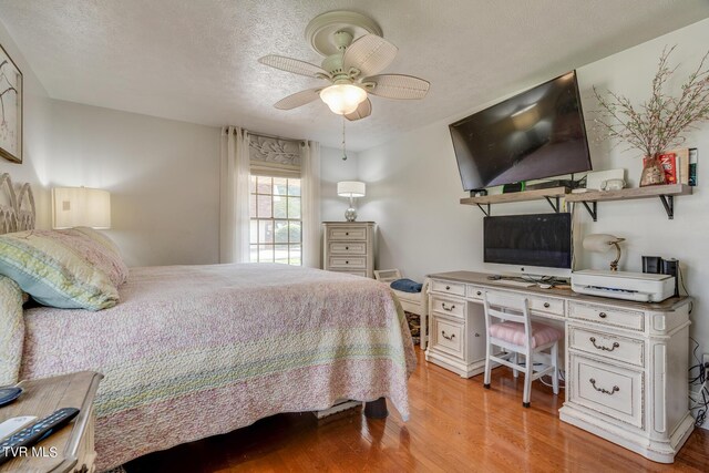 bedroom with light wood-type flooring, ceiling fan, and a textured ceiling