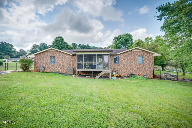 rear view of house featuring a sunroom and a yard