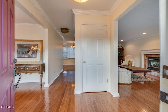 entrance foyer with crown molding, hardwood / wood-style floors, and a brick fireplace