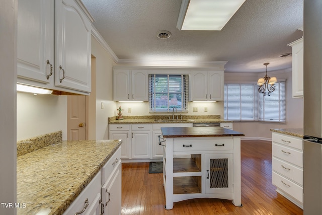 kitchen featuring light hardwood / wood-style flooring, white cabinetry, butcher block counters, and ornamental molding