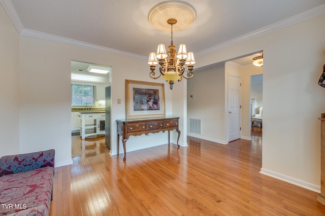 dining room with a notable chandelier, crown molding, and light hardwood / wood-style flooring