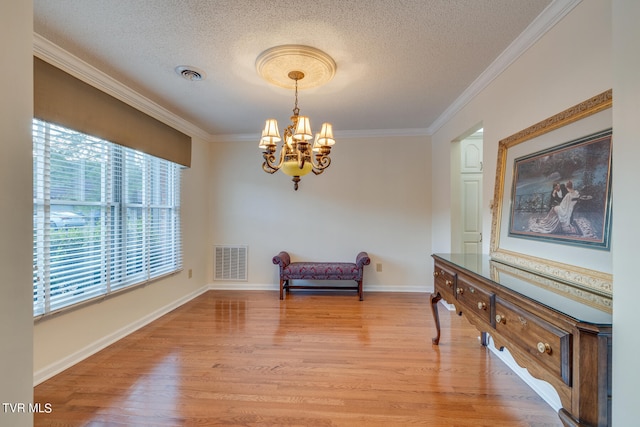 sitting room with a textured ceiling, light hardwood / wood-style flooring, a chandelier, and ornamental molding