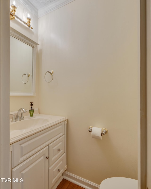 bathroom featuring toilet, vanity, ornamental molding, hardwood / wood-style flooring, and a textured ceiling