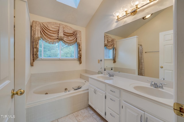 bathroom with lofted ceiling with skylight, tile patterned flooring, tiled tub, and vanity