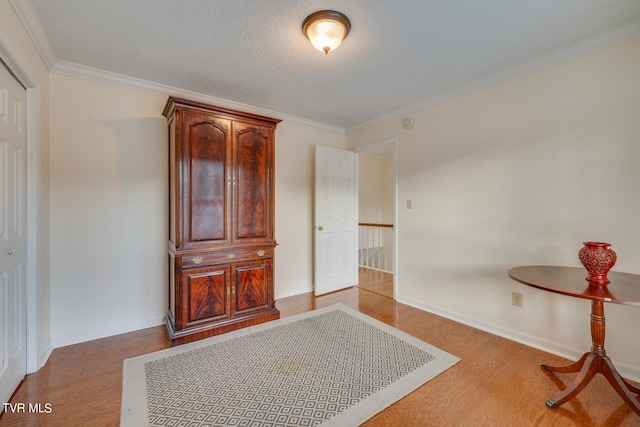 bedroom featuring hardwood / wood-style floors, crown molding, and a textured ceiling