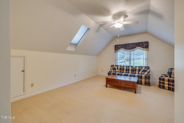 interior space with a textured ceiling, ceiling fan, and lofted ceiling with skylight