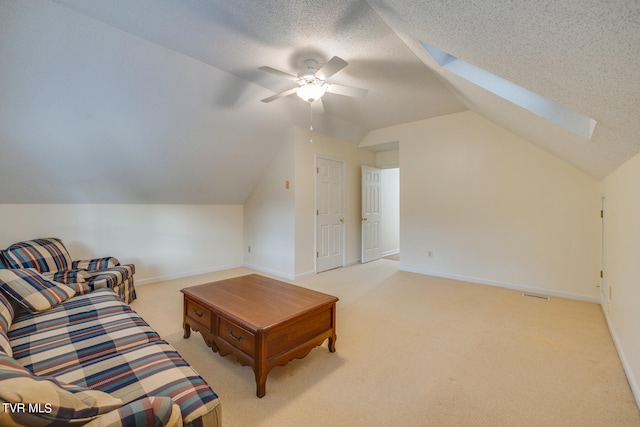 carpeted living room featuring ceiling fan, lofted ceiling with skylight, and a textured ceiling