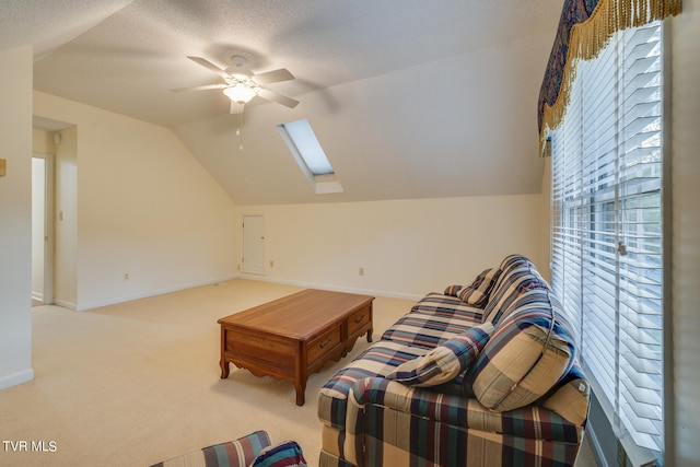 living room featuring vaulted ceiling with skylight, ceiling fan, a textured ceiling, and light carpet