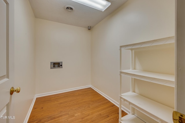 laundry room featuring a textured ceiling, light hardwood / wood-style floors, and washer hookup