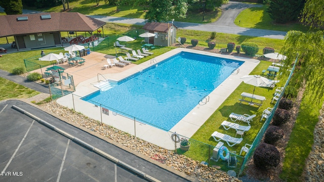 view of swimming pool featuring a patio, an outdoor structure, and a lawn