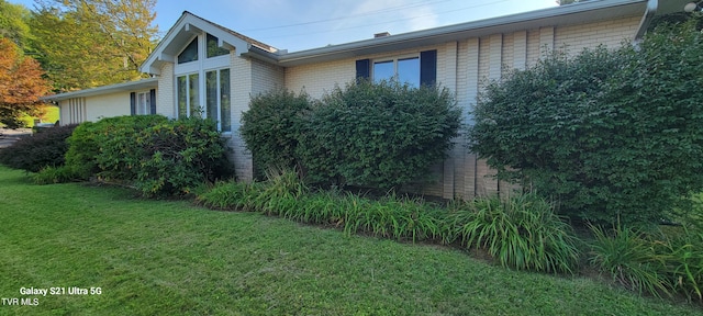 view of side of home with brick siding and a yard