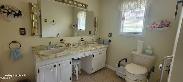 bathroom with double vanity, tile patterned flooring, toilet, and a sink