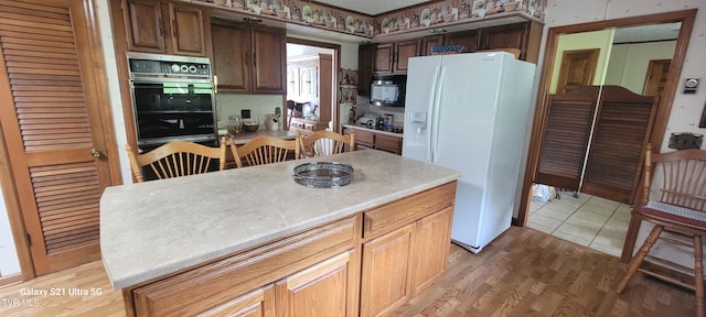 kitchen featuring light countertops, light wood finished floors, and black appliances