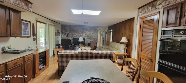 kitchen with light countertops, light wood-type flooring, a skylight, and dobule oven black