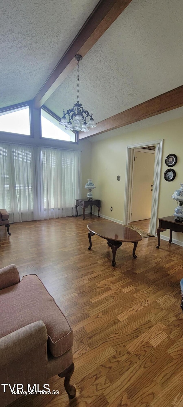 living room featuring a textured ceiling, lofted ceiling with beams, wood finished floors, and baseboards