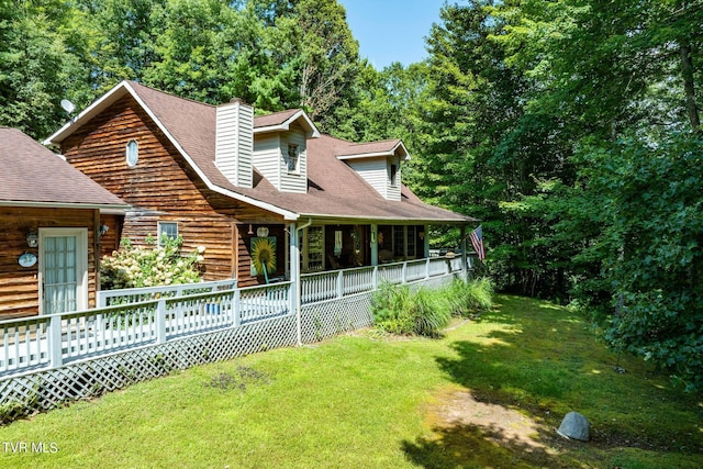 view of side of home featuring roof with shingles, a chimney, and a yard