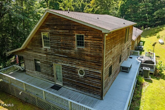 view of side of property featuring cooling unit, a wooden deck, and a lawn