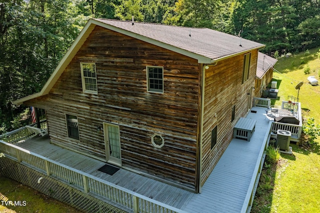 view of property exterior featuring central air condition unit, a shingled roof, a view of trees, and a wooden deck