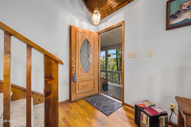 foyer featuring wood ceiling, light hardwood / wood-style floors, and a towering ceiling